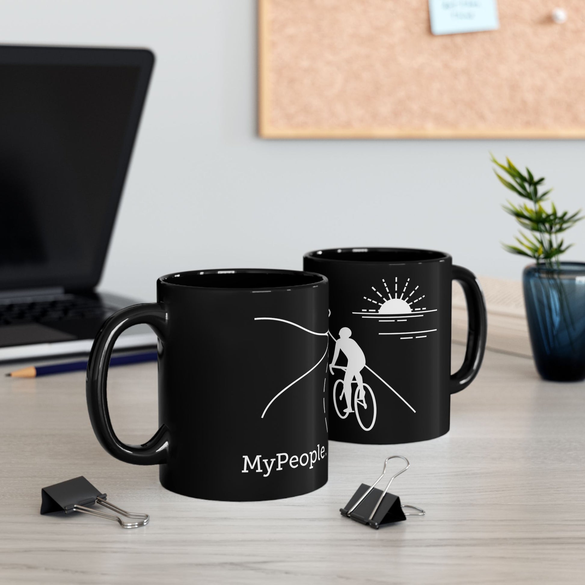 Two ceramic mugs featuring the MyPeople Cycling line illustration sitting on a desk.