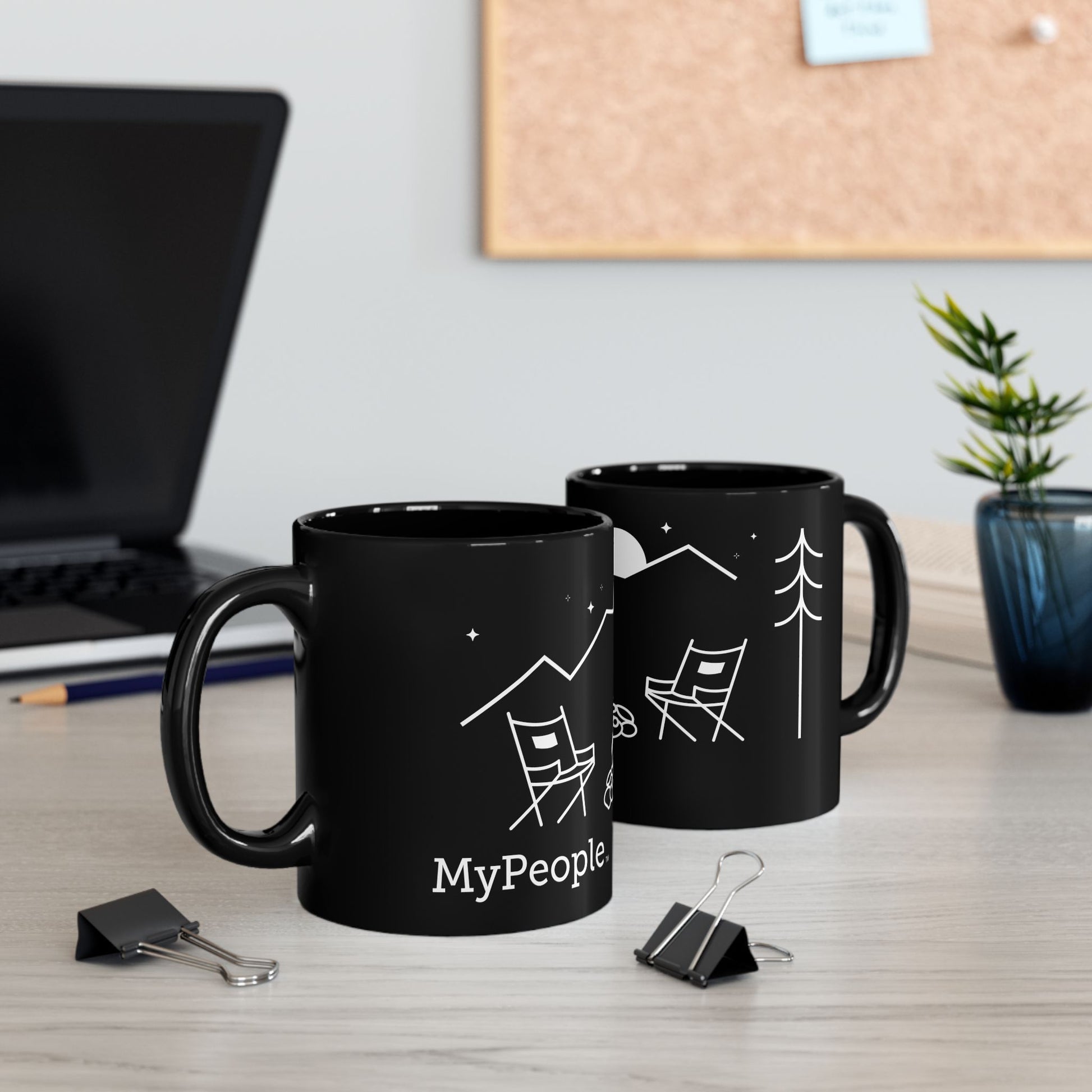 Two ceramic mugs featuring the MyPeople Campfire line illustration sitting on a desk.