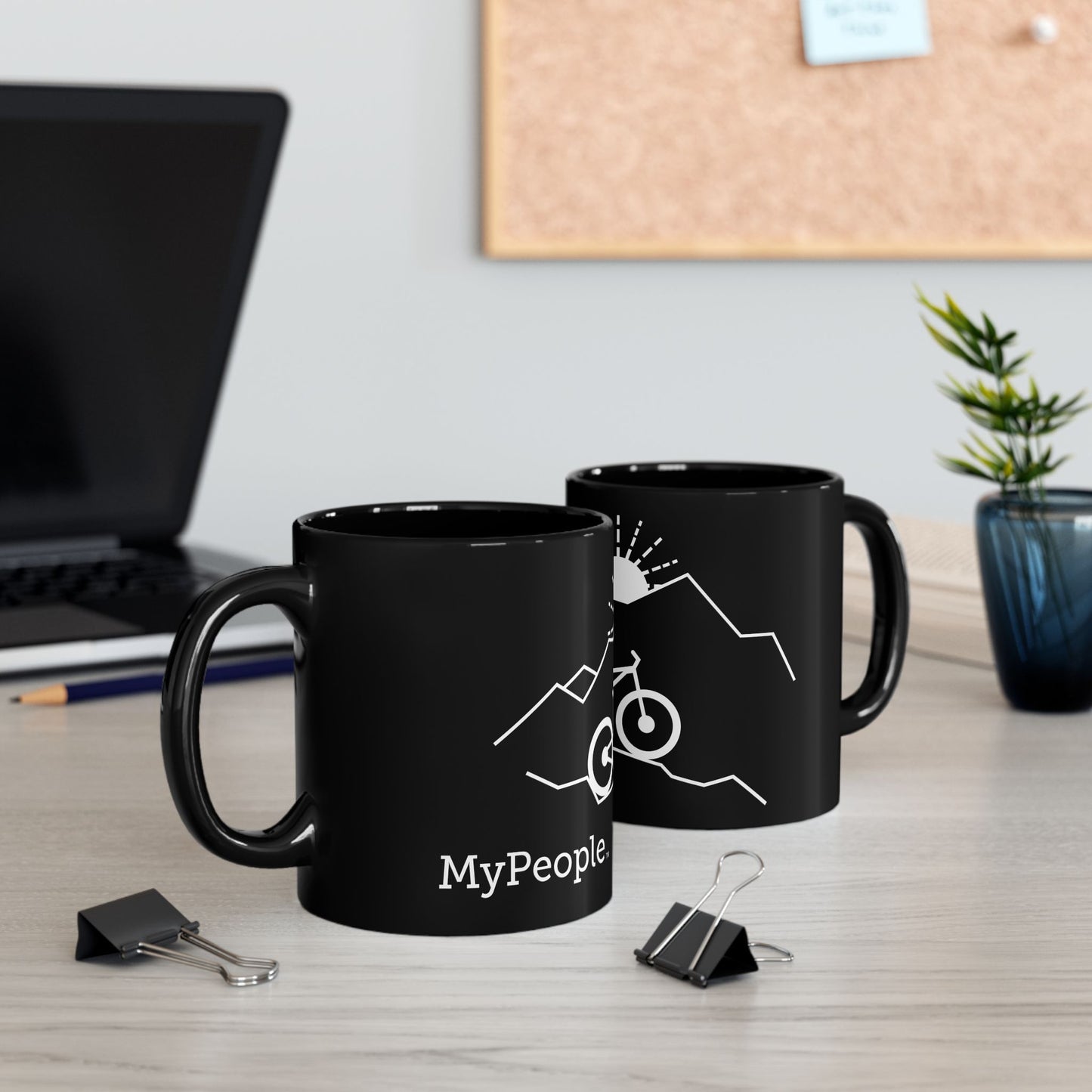 Two ceramic mugs featuring the MyPeople Mountain Biking line illustration sitting on a desk.